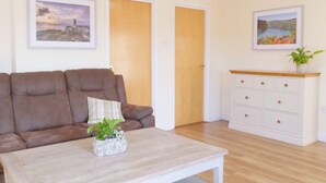 A living room with a brown sofa, a white coffee table with a plant, and a white dresser with drawers. - Light, Bright Apartment Tucked Away by Bordeaux Harbour (Vale)