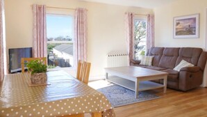 A living room with a sofa, a table, and a TV. - Light, Bright Apartment Tucked Away by Bordeaux Harbour (Vale)