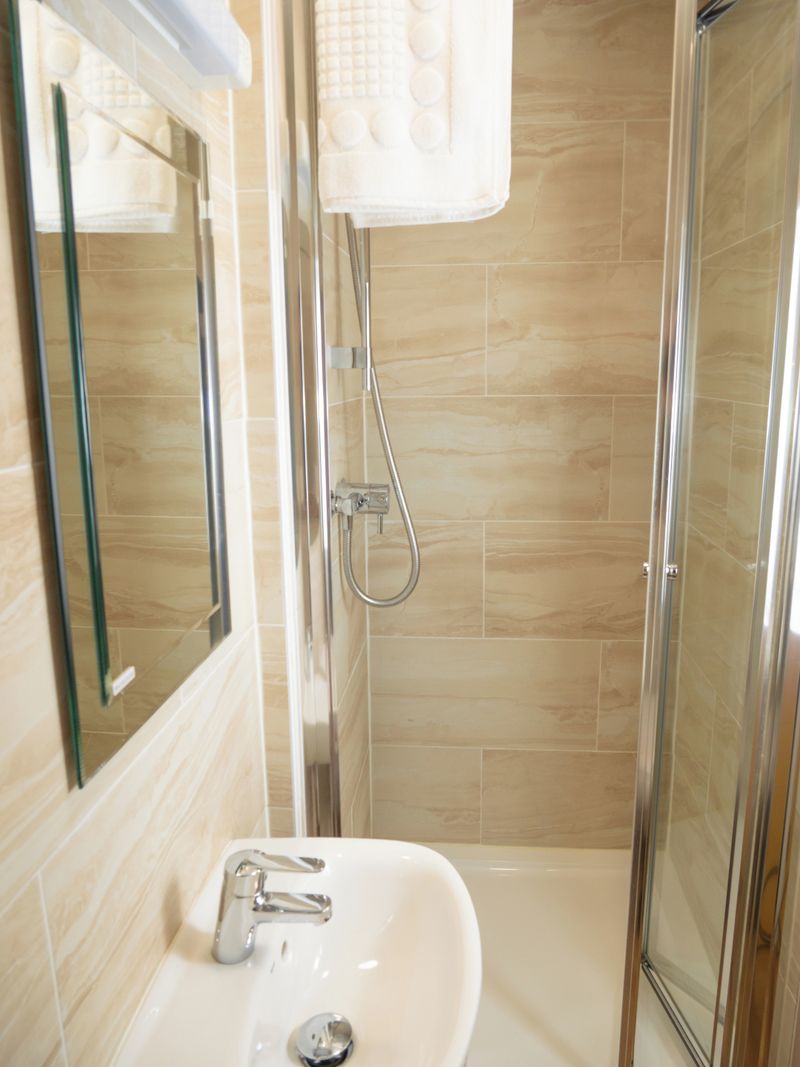 A bathroom with a sink, mirror, and shower.