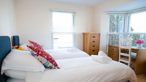Une chambre avec deux lits, un bureau en bois et une chaise.
