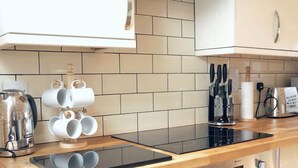 A modern kitchen with a black induction cooktop, stainless steel appliances, and a wooden countertop.