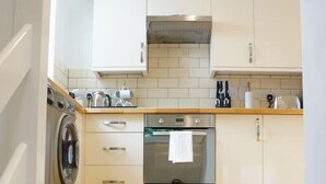 A modern kitchen with white cabinets, a built-in oven, and a washing machine.