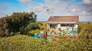 A beachside cafe with outdoor seating and a view of the ocean.