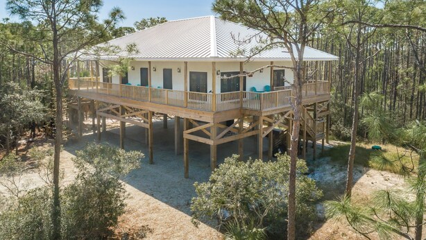 A wooden house with a balcony, surrounded by trees. - Brand New 3 Bedroom, Pet Friendly Amazing Bay View Home (St George Island)