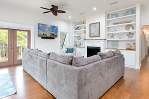 A living room with a grey sectional sofa, a fireplace, and a bookshelf with decorative items. - Brand New 3 Bedroom, Pet Friendly Amazing Bay View Home (St George Island)