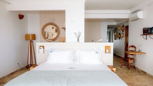 Una habitación de hotel con una cama grande, una lámpara de pie, un adorno en la pared y una pequeña mesa con una silla.