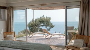 Un dormitorio con una cama grande, vistas al mar y un balcón con sillas y una mesa.