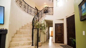 Un escalier en colimaçon avec une rampe en métal, un pot de fleurs et une porte en bois.