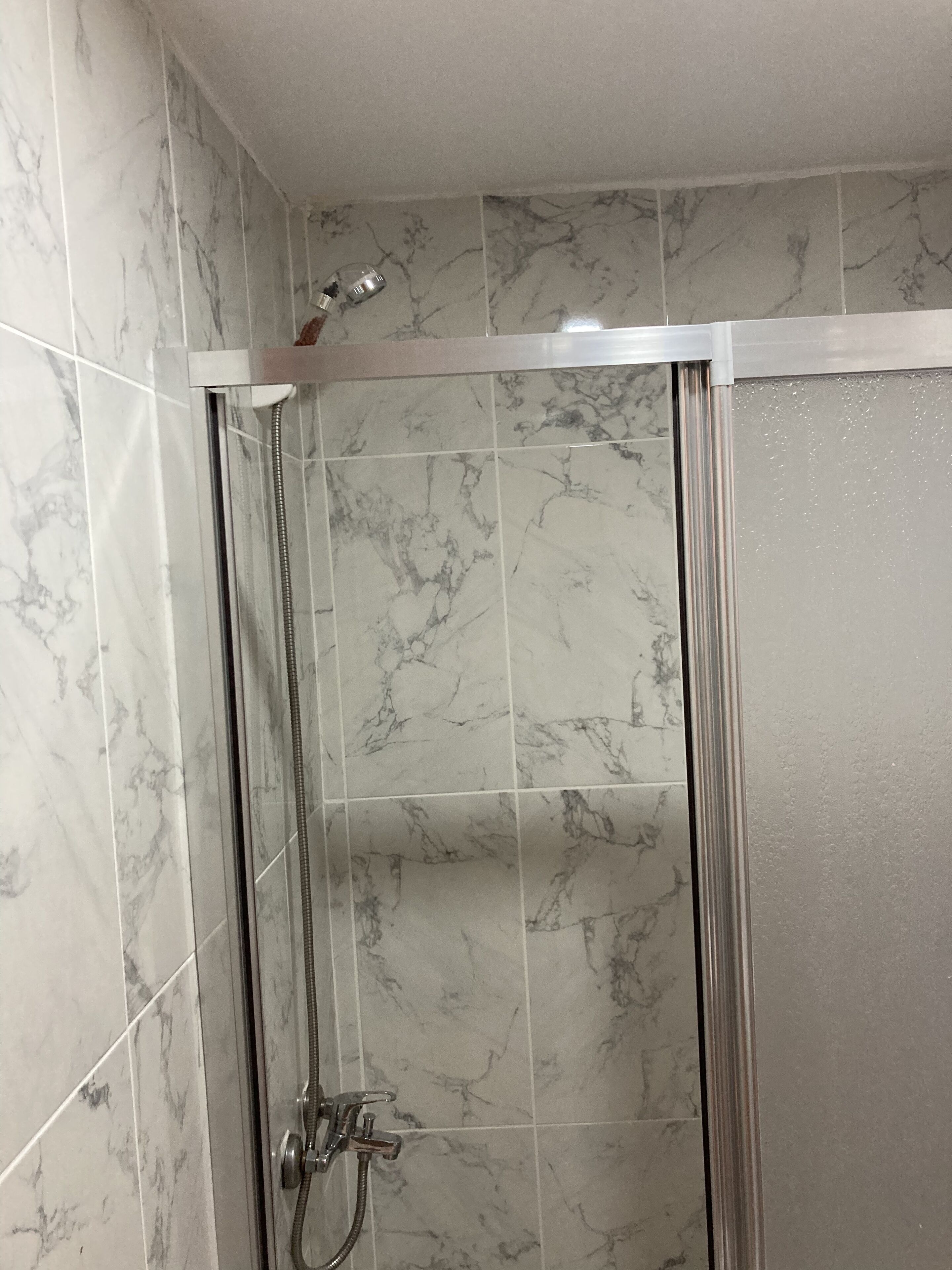 A shower with a glass door and a handheld showerhead.