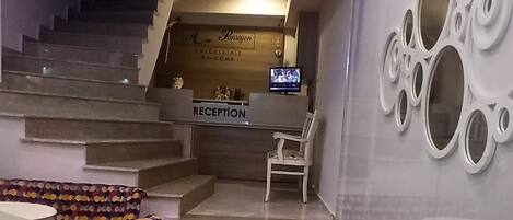 Un hall de hotel con mostrador de recepción, una escalera y una silla estampada.