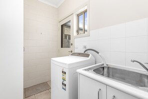 A compact laundry room with a washing machine, a sink, and a window. - Edwards - Family friendly, pet friendly (Apollo Bay)