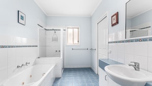 A bathroom with a bathtub, a sink, and a shower area.