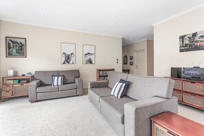 A living room with two grey sofas, a coffee table, a bookshelf, and framed pictures on the wall. - Edwards - Family friendly, pet friendly (Apollo Bay)