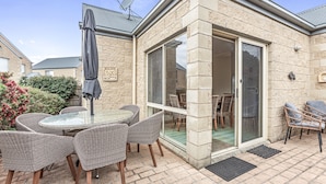 A covered patio area with a glass door leading to an indoor space, wicker furniture, and a satellite dish on the roof.