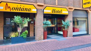 The exterior of Montana Hotel with a brick facade, large windows, and potted plants. - Montivo Hotel Köln-Bonn Airport (Troisdorf)