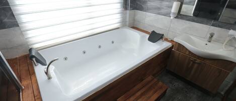 A modern bathroom with a freestanding bathtub, a wooden vanity, a sink, and a mirror.