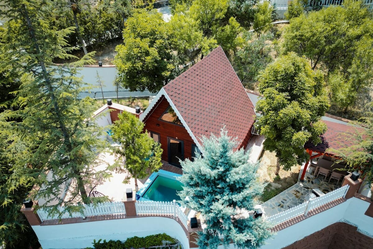 A house with a red roof, a swimming pool, and a white picket fence.