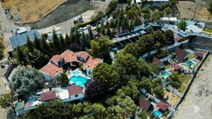 Vue aérienne d’un complexe hôtelier comprenant plusieurs bâtiments, des piscines et un paysage rocheux.