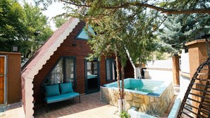 Un espace extérieur moderne doté d’une structure en bois, d’un bain à remous en pierre et d’un canapé bleu.