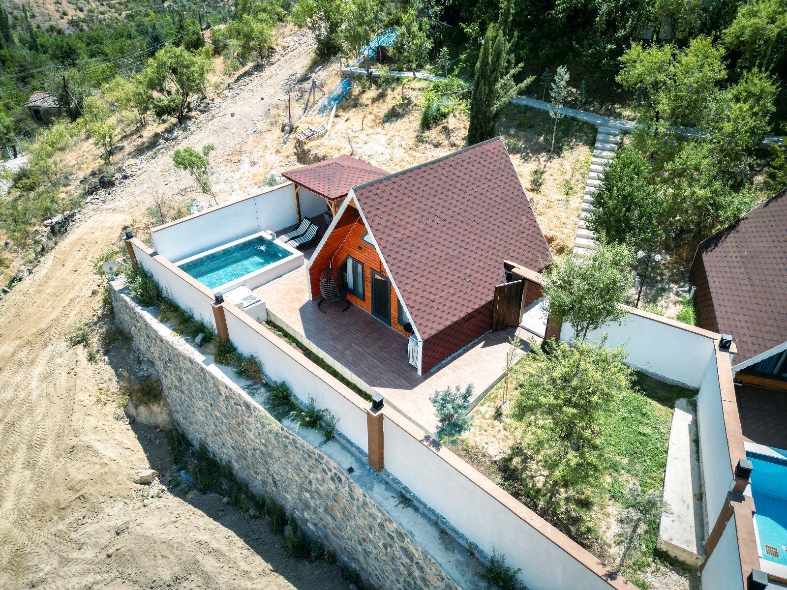 Ein Haus mit Swimmingpool, Steinmauer und einem Gebäude mit rotem Dach.