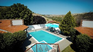 A swimming pool with lounge chairs and umbrellas, surrounded by greenery and hills. - ÇELİK RESORT (Ayas)