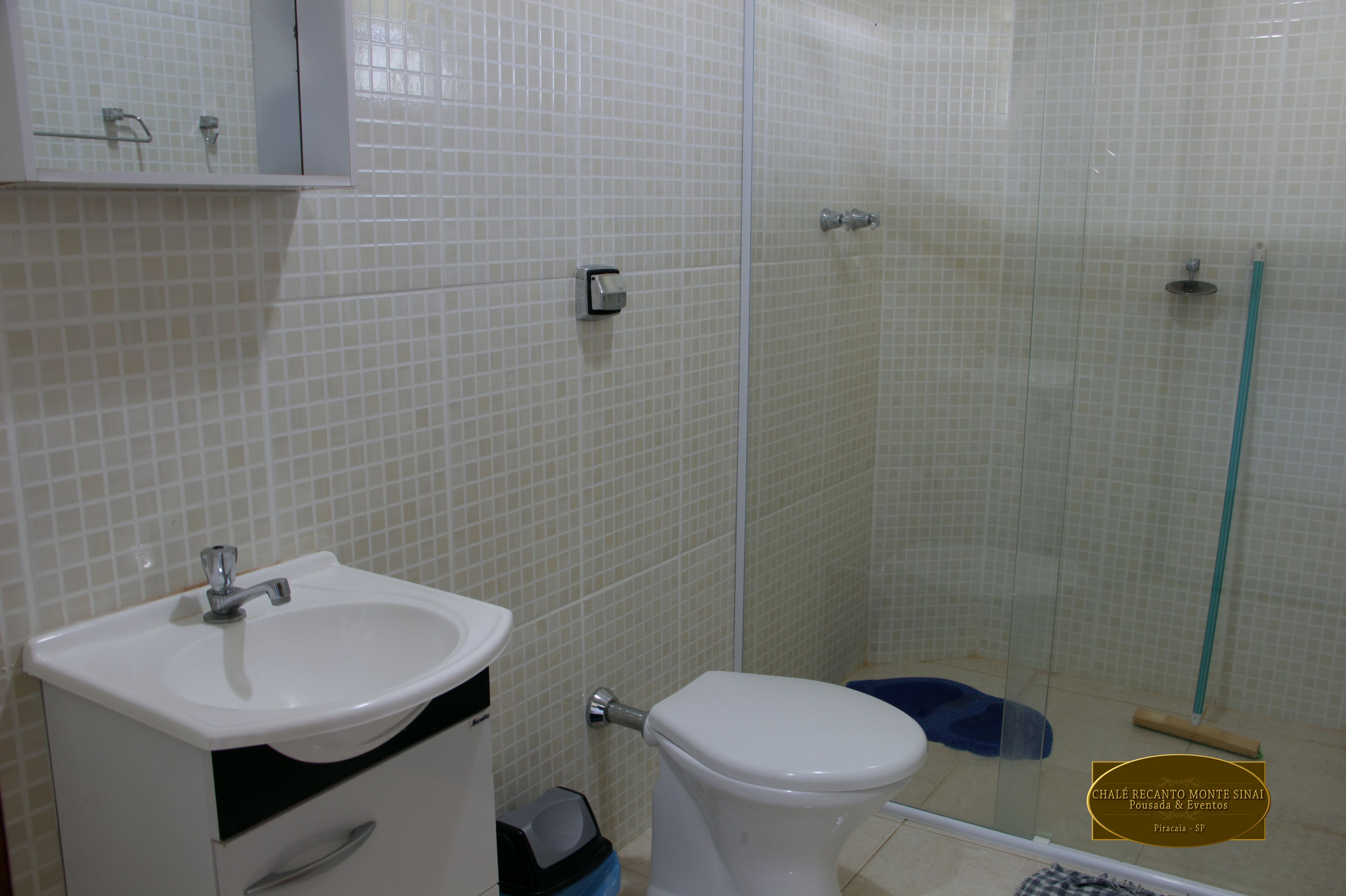 Un baño con lavamanos blanco, inodoro y cabina de ducha con paredes de vidrio.