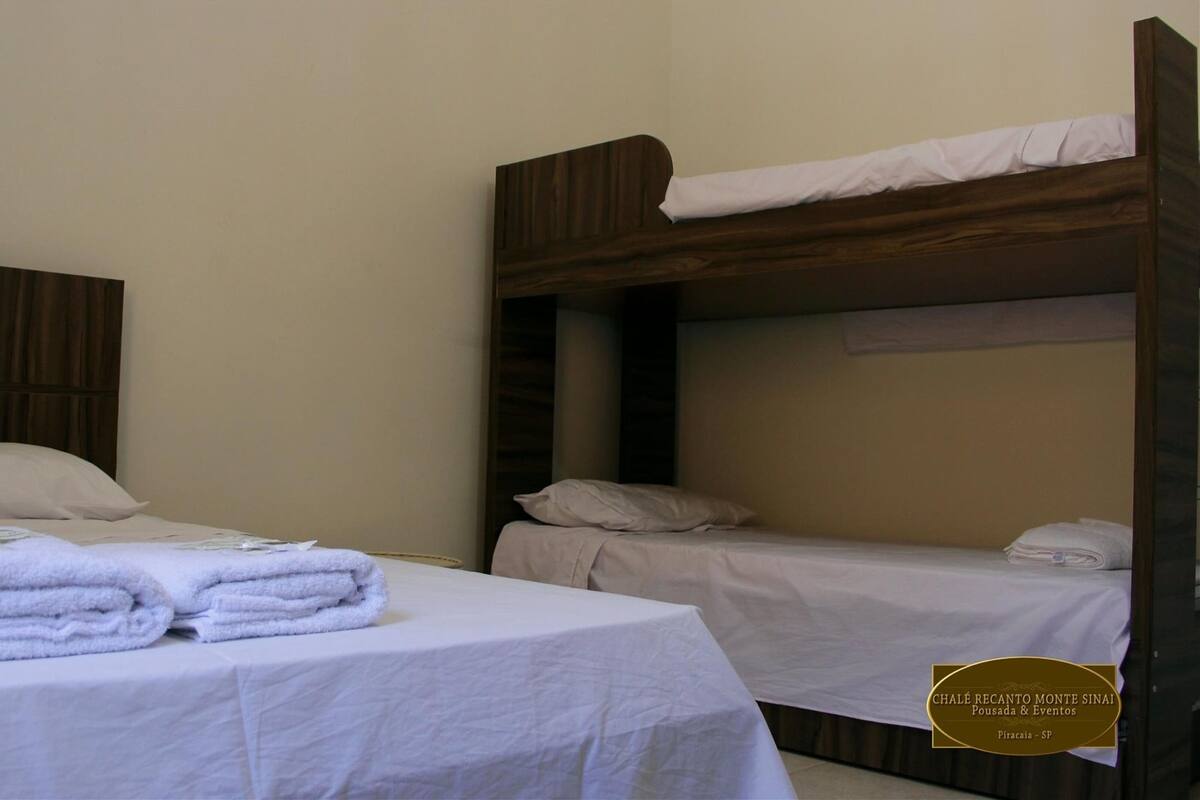 A hotel room with two single beds, each with a wooden headboard and white bedding. There are folded towels on the beds.