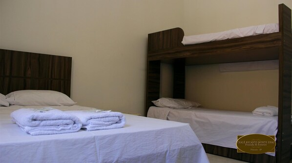 A hotel room with two single beds, each with a wooden headboard and white bedding. There are folded towels on the beds.
