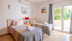 Ein Hotelzimmer mit zwei Betten, einer roten Lampe und einem Gemälde mit Strandmotiv.