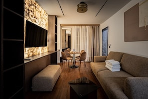 Une chambre d’hôtel moderne équipée d’un canapé, d’une petite table, d’une télévision et d’un coin repas avec des chaises.