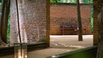 A brick wall with a bench and a tree in a shaded area.