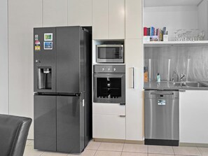 Une cuisine compacte équipée d’un réfrigérateur, d’un four à micro-ondes, d’un four et d’un lave-vaisselle.