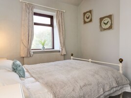 Un dormitorio con cama, una ventana con cortinas, un radiador y dos cuadros con mariposas en la pared.