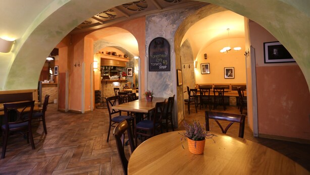 An interior with arched ceilings, wooden tables and chairs, and a menu board. - U Cervene Zidle (Prague)