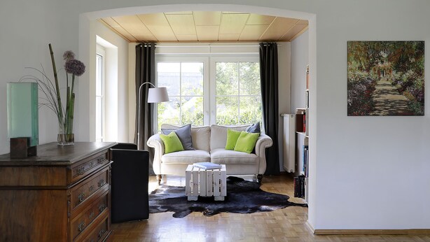 Ett vardagsrum med en vit soffa, ett träskåp och en svart lädermatta.