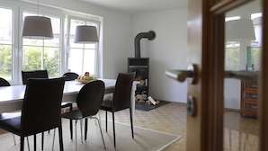 En matplats med ett bord och stolar, en öppen spis och utsikt genom en dörr.