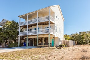 A two-story building with a balcony on the second floor, a visible door, and a number '1018' on the front. - Sandy Bottoms - 4 Bedroom Home - Private Pool! (Surf City)