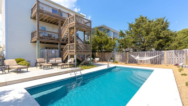 Ein Schwimmbecken mit einer Holzterrasse und Gartenmöbeln.