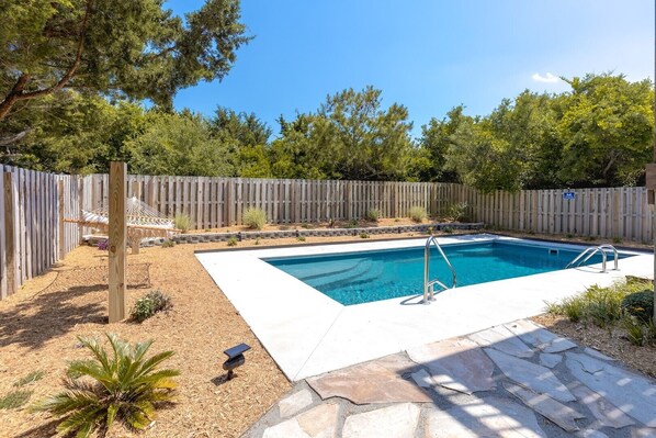 A rectangular swimming pool with a wooden deck, surrounded by a wooden fence, and a hammock. - Sandy Bottoms - 4 Bedroom Home - Private Pool! (Surf City)