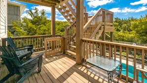 Une terrasse en bois avec une table et des chaises en verre, une piscine et un escalier.