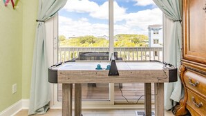 Une table de billard dans une pièce donnant sur un balcon et un espace extérieur.
