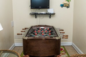 A foosball table in a room with a television mounted on the wall. - Sea-Esta! 4BR Townhome with Community Pool & easy beach access! (Surf City)