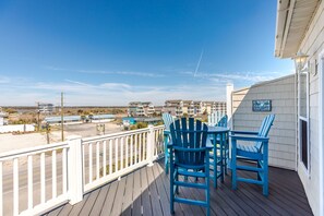 A deck with blue chairs and a view of a beach and buildings. - Sea-Esta!  4BR Townhome with Community Pool & easy beach access! (Surf City)