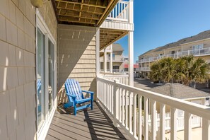 A balcony with a blue chair, white railings, and a view of other buildings. - Sea-Esta! 4BR Townhome with Community Pool & easy beach access! (Surf City)