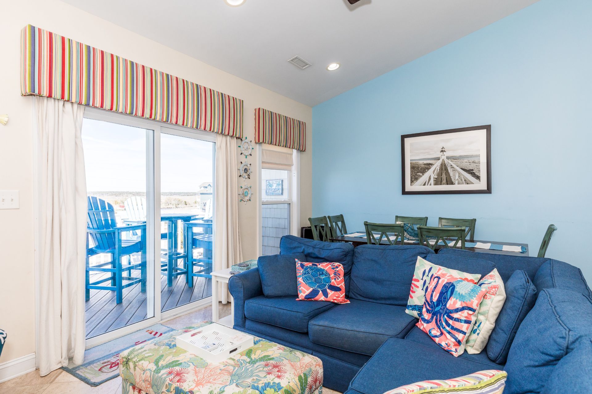 A living room with a blue sofa, a coffee table, and a view of the deck.