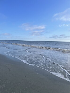 Ein Strand mit sanft anschwellenden Wellen unter blauem Himmel.