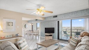 Een moderne woonkamer met een bank, salontafel, tv en een balkon met uitzicht over de stad.