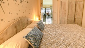Une chambre à coucher avec un lit, une literie à motifs, un mur décoré de motifs de pissenlits et une armoire.