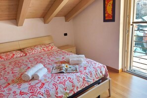 Ein Schlafzimmer mit einem Bett, einem Nachttisch, einem Fenster mit Aussicht und einem Bild an der Wand.
