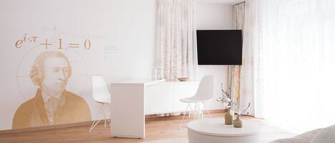 A modern living room with a white desk, a flat-screen TV, and a large wall mural.